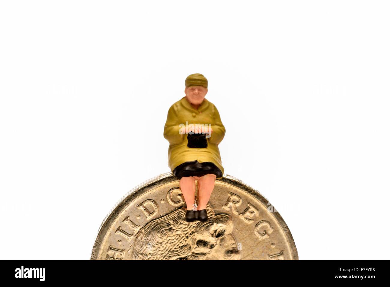 Femmina miniaturizzati pensionato seduto su una libbra di moneta Foto Stock
