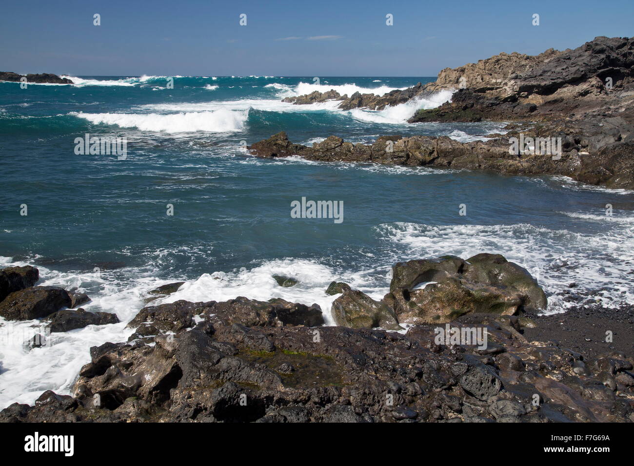 Caletta rocciosa con surf a Playa de la madera, Parque Natural de Los Volcanes, Lanzarote. Foto Stock