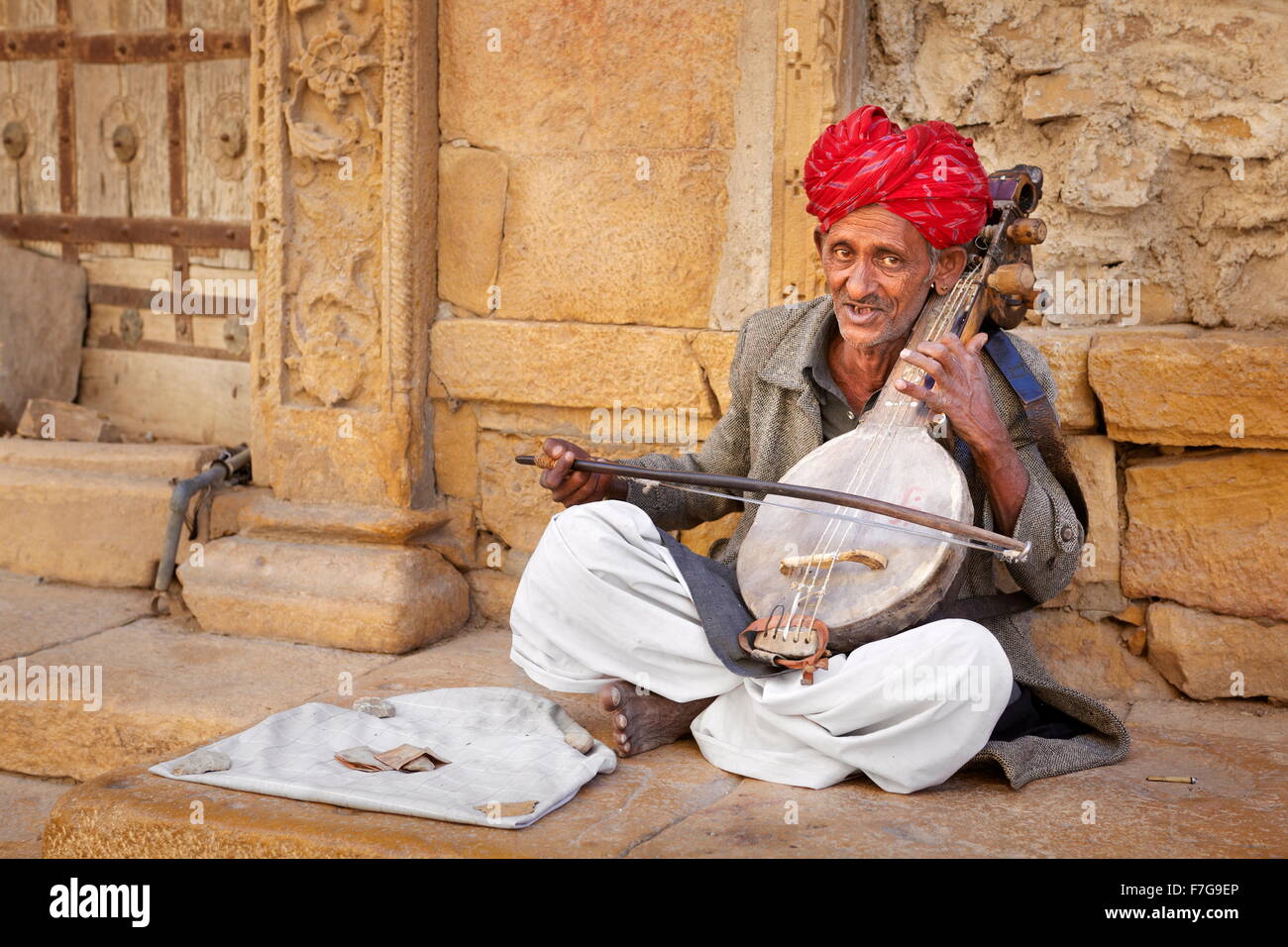 Ritratto di musicista dell'india indossando un turbante di lettura la riproduzione sulla strada, Jaisalmer, Rajasthan, India Foto Stock