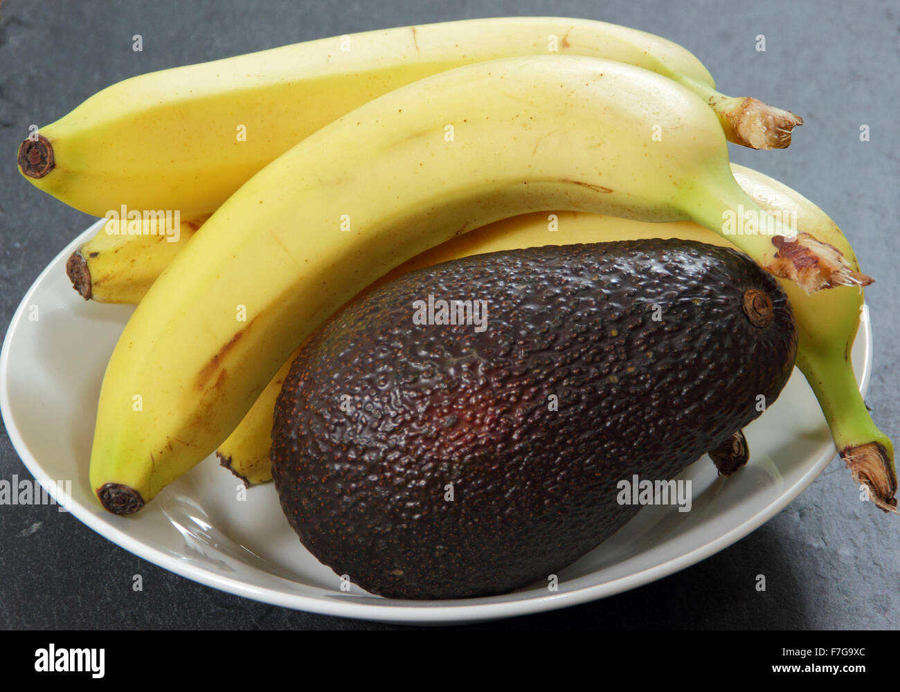 Le banane in una ciotola con un avocado per accelerare il processo di maturazione - impostazione domestica , REGNO UNITO Foto Stock