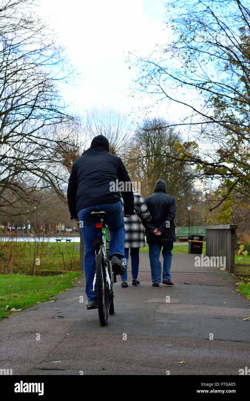 Ciclista sul sentiero dietro la coppia di anziani tenendo le mani Foto Stock