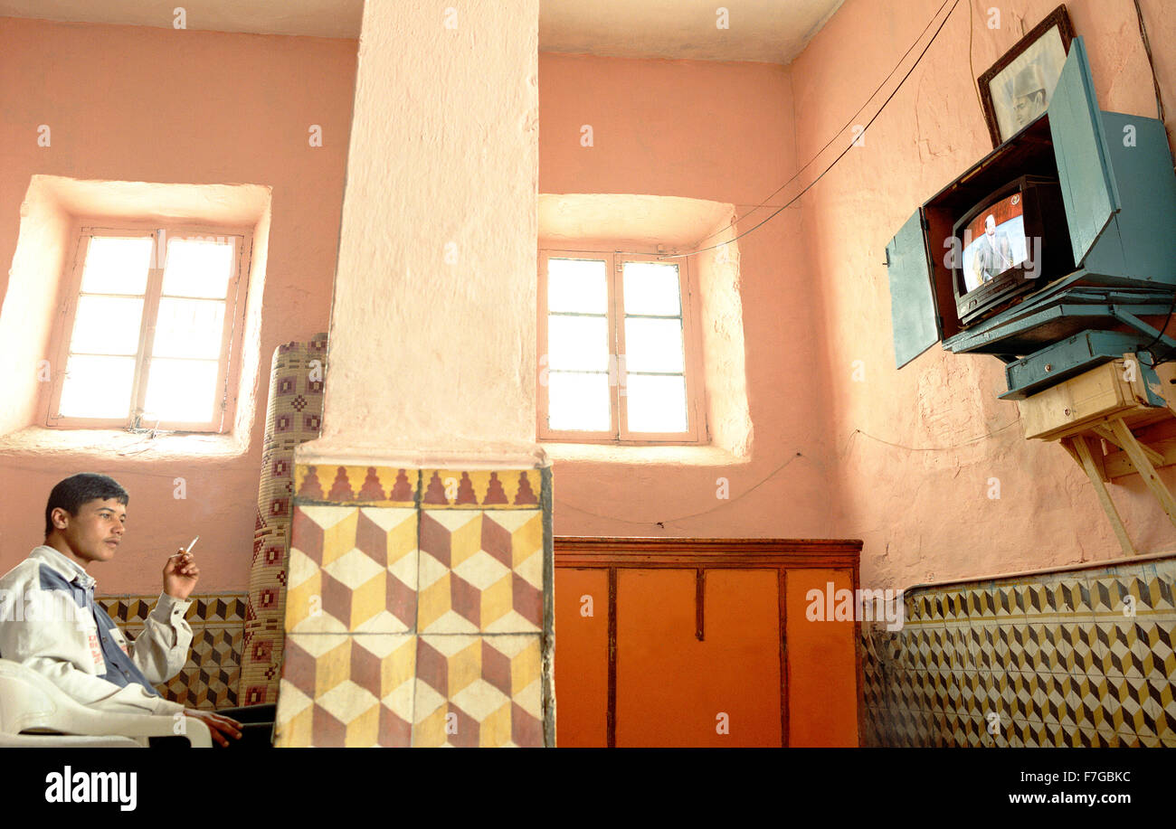 Un marocchino uomo fuma una sigaretta e guarda la televisione all'interno di un Essaouira cafe. Il Marocco, Africa del Nord. Foto Stock