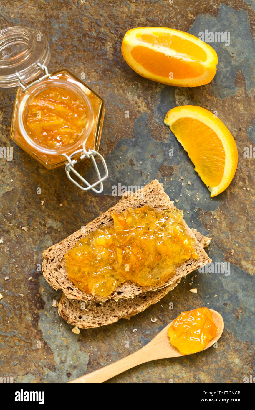 Inceppamento arancione sul pane integrale a fette, fotografato overhead su ardesia con luce naturale (messa a fuoco selettiva) Foto Stock