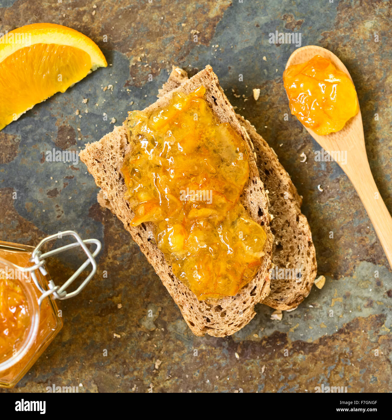 Inceppamento arancione sul pane integrale a fette, fotografato overhead su ardesia con luce naturale (messa a fuoco selettiva) Foto Stock
