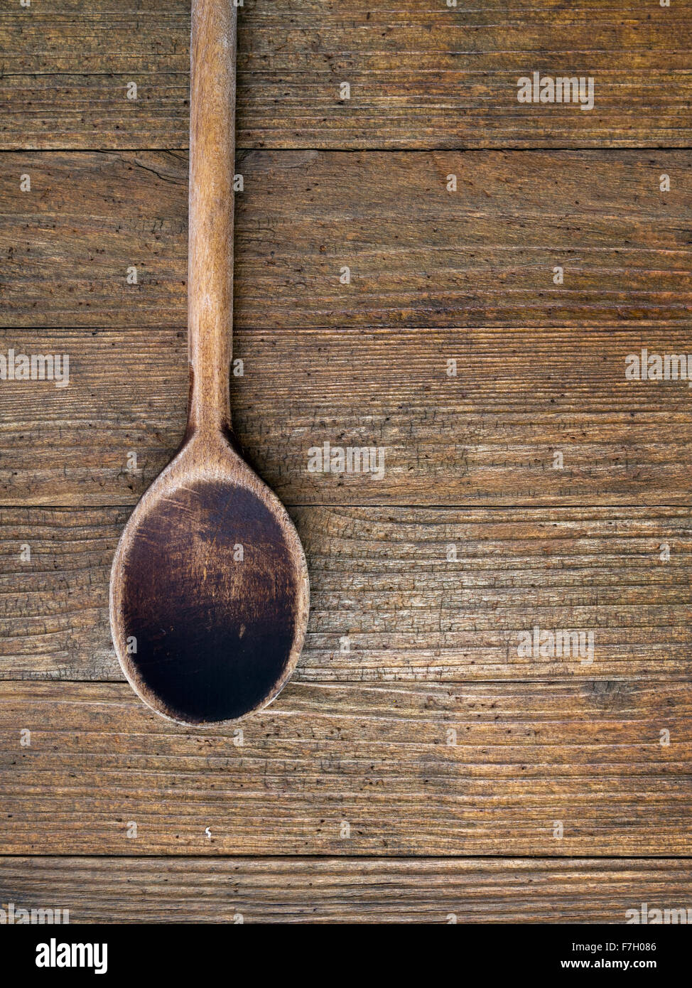 Vecchio, è ben utilizzato il cucchiaio di legno sul legno scuro dello sfondo. Composizione verticale. Foto Stock