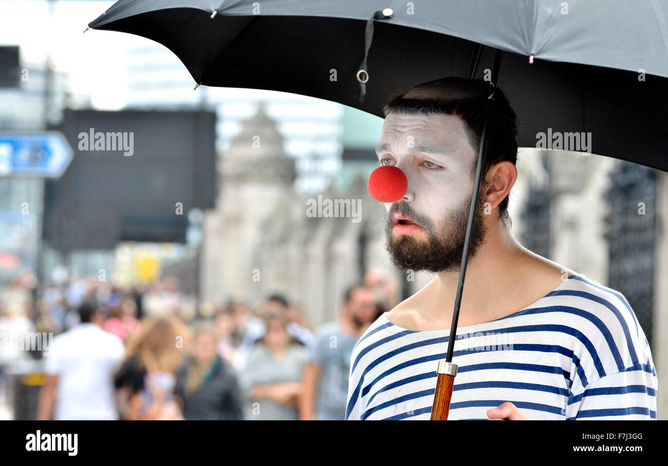 Londra, Inghilterra, Regno Unito. Clown con un ombrello in piazza del Parlamento Foto Stock