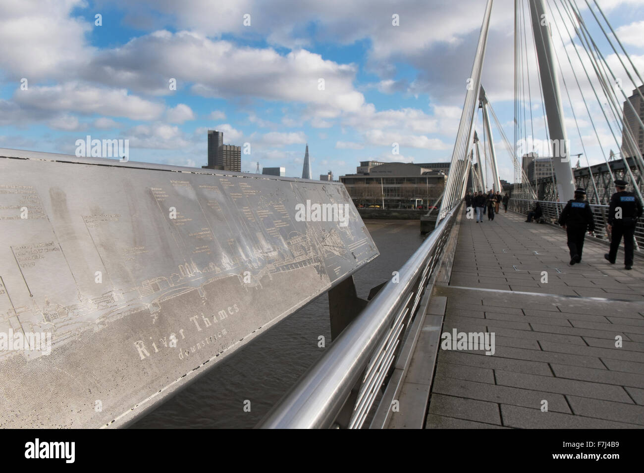 Un poliziotto e polizia Donna che cammina attraverso uno dei Golden Jubilee piedi ponti sul fiume Thames, London, England, Regno Unito Foto Stock