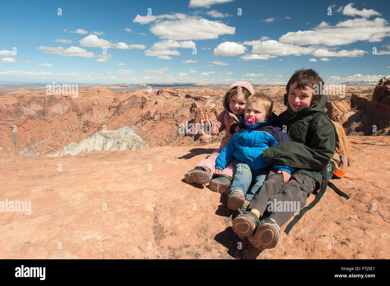 Bambini seduti a bordo del canyon nel Parco Nazionale di Canyonlands, Utah, Stati Uniti d'America Foto Stock