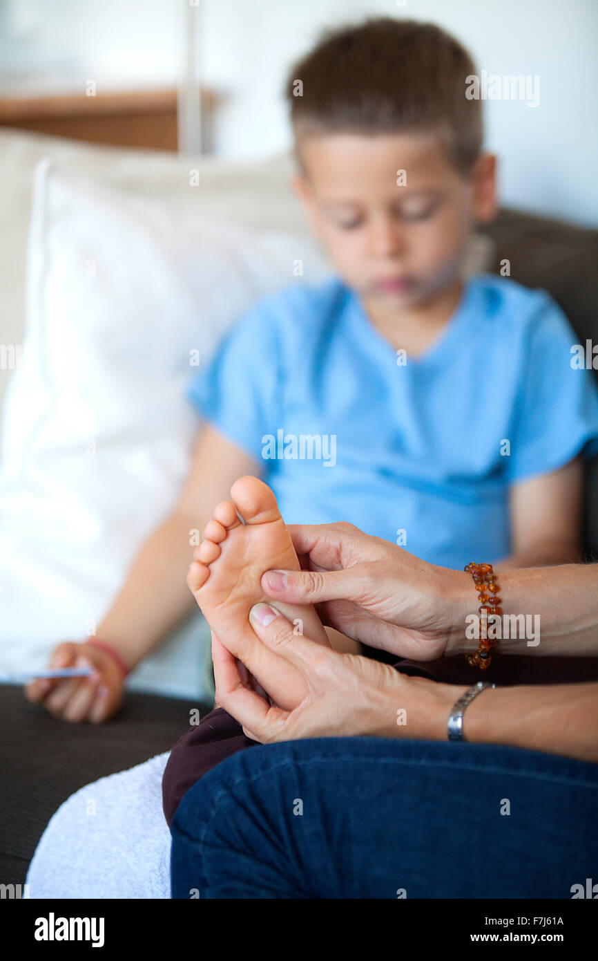 Reportage su riflessologia plantare per i bambini. Il reflexologist si occupa di bambini dai 5 anni in poi verso l'alto. La riflessologia agisce sulla loro concentrazione, memoria, equilibrio e serenità e dormire. 5 anno vecchio ragazzo in una sessione. Foto Stock