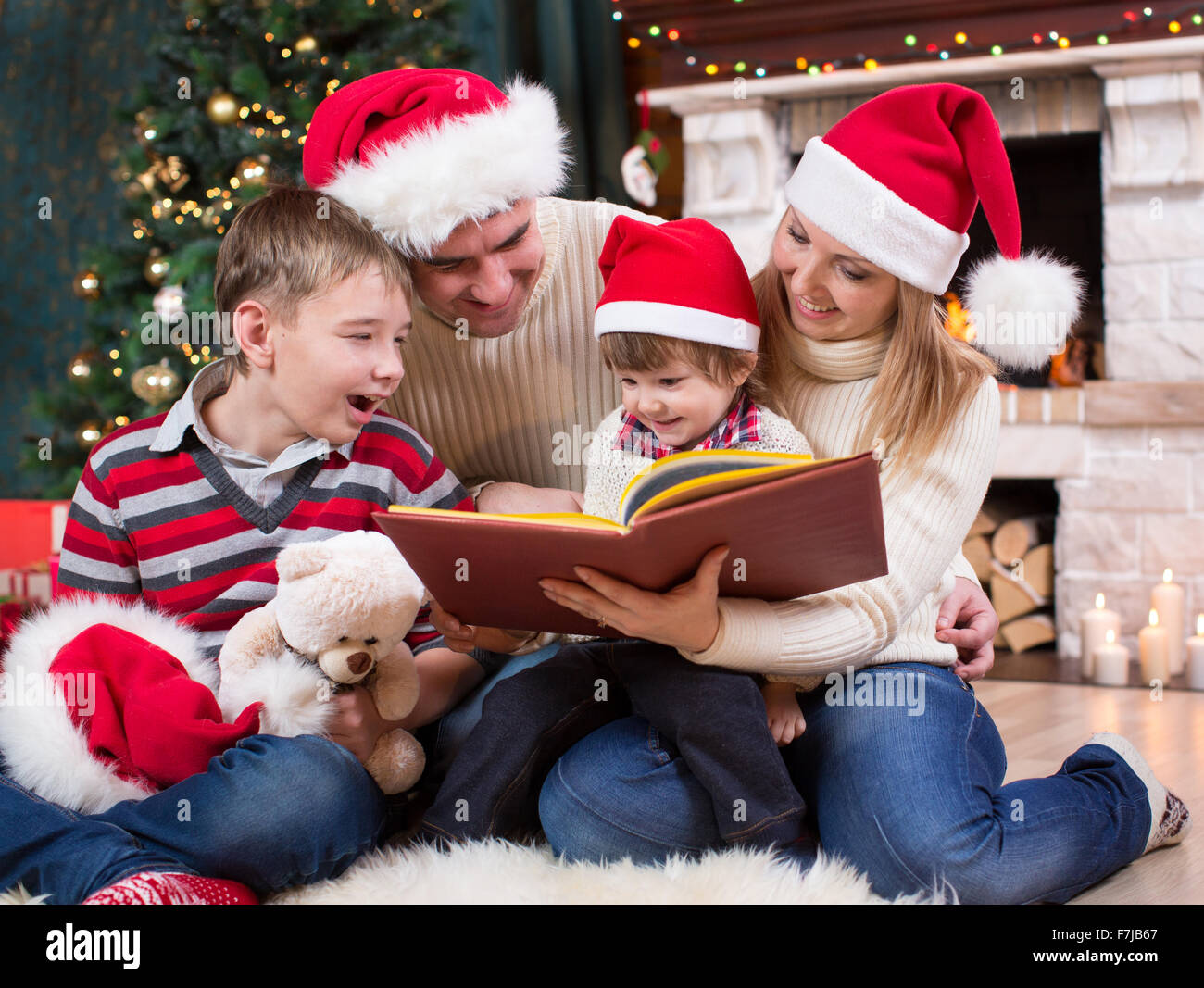 Famiglia leggendo un libro nella parte anteriore dell albero di Natale Foto Stock