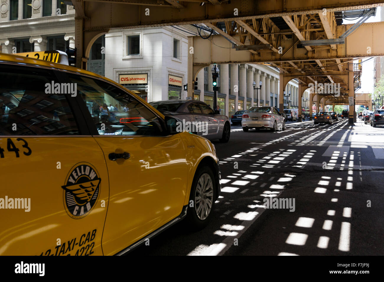 Un giallo taxi su South Wells Street al di sotto del Chicago L, ferrovia sopraelevata. Foto Stock