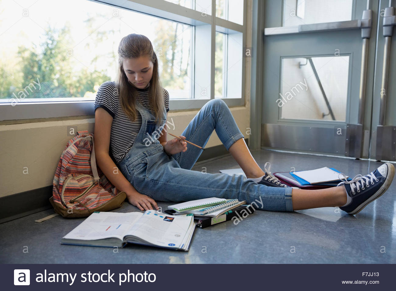 Studente di scuola superiore con il libro di testo lo studio sul pavimento Foto Stock