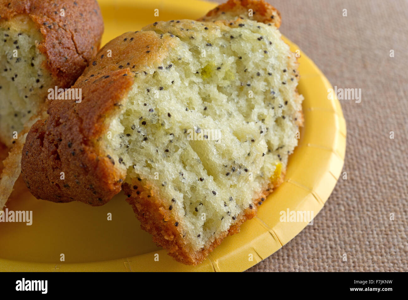 Chiudere la vista di un pane appena sfornato di pepe al limone muffin prima colazione che è stato rotto in metà su una piastra di colore giallo Foto Stock