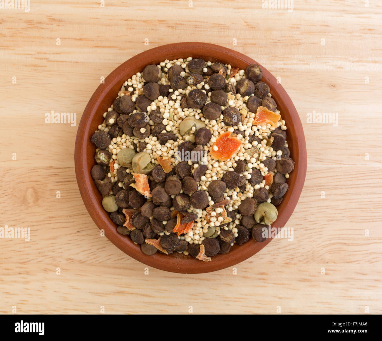 Vista dall'alto di una piccola ciotola riempita con gli ingredienti secchi per la quinoa, zuppa di lenticchie isolato su una tavola di legno top Foto Stock