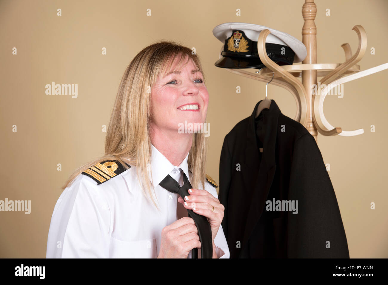 Femmina navale comandante Lt getting pronto per legatura a dovere il suo nero cravatta uniforme Foto Stock