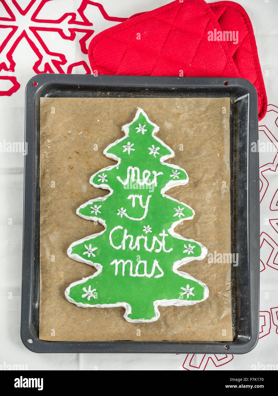 Fatti in casa a base di albero di natale-simili gingerbread cookie con glassa verde e Buon Natale scritta sul vassoio da forno Foto Stock