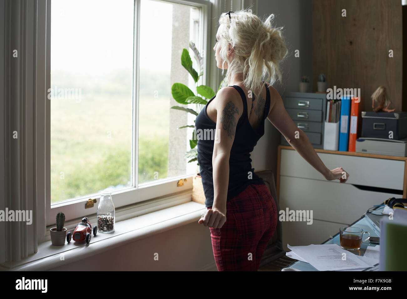 Giovane donna stretching in corrispondenza della finestra in home office Foto Stock