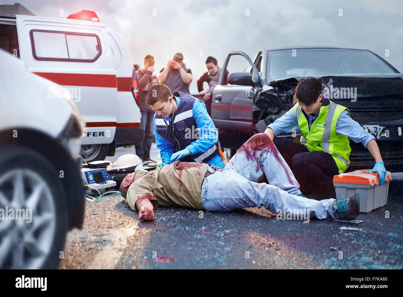 Gli operatori di soccorso tendente al sanguinoso incidente di auto vittima in strada Foto Stock