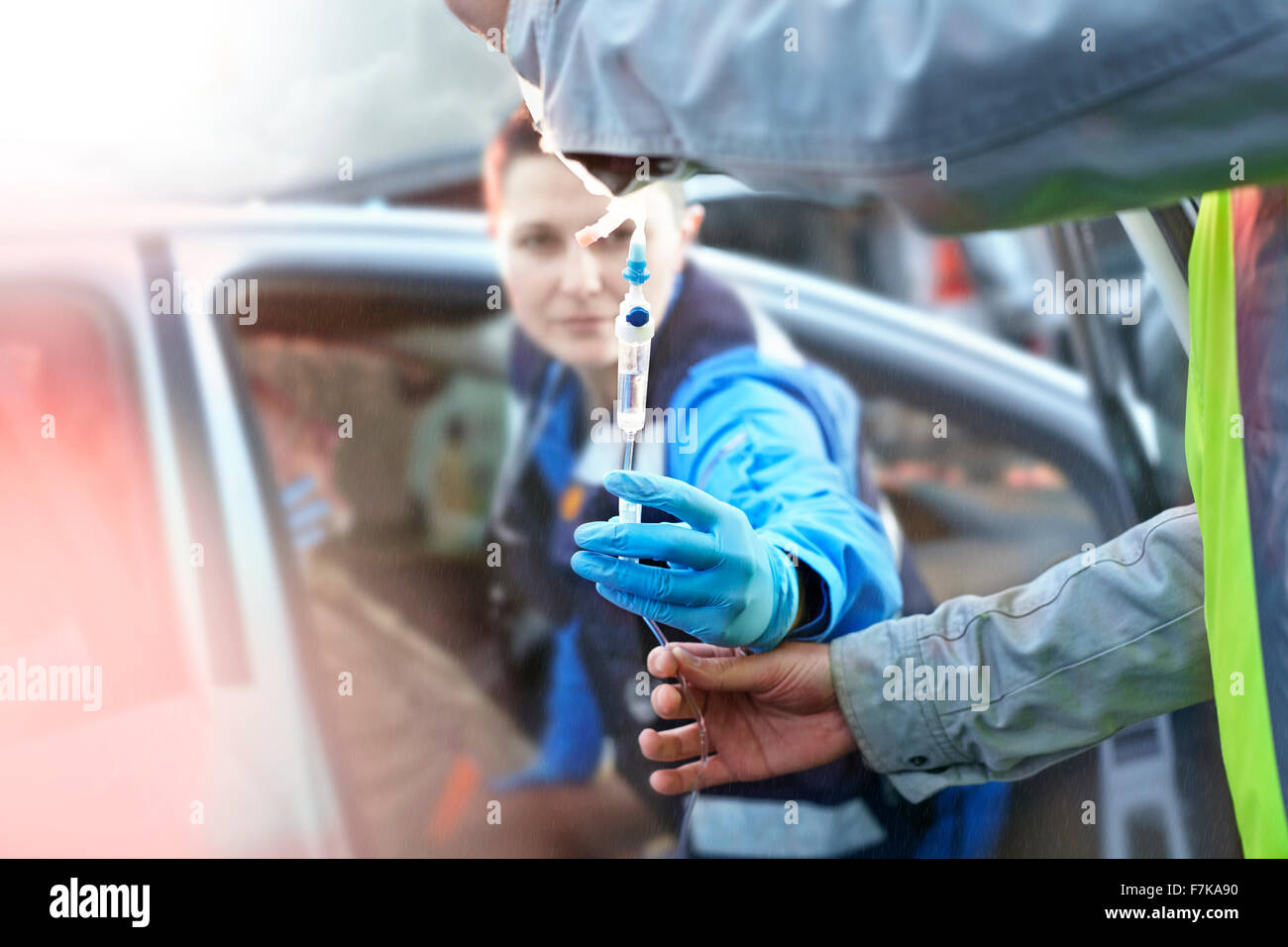Gli operatori di soccorso con flebo IV tendente ad auto vittima di incidenti in auto Foto Stock
