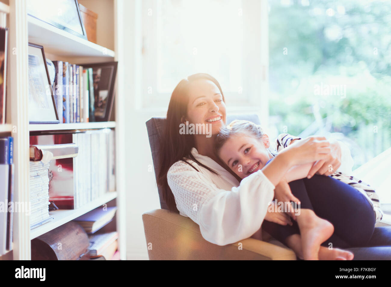 Affettuosa madre abbracciando la figlia in poltrona Foto Stock