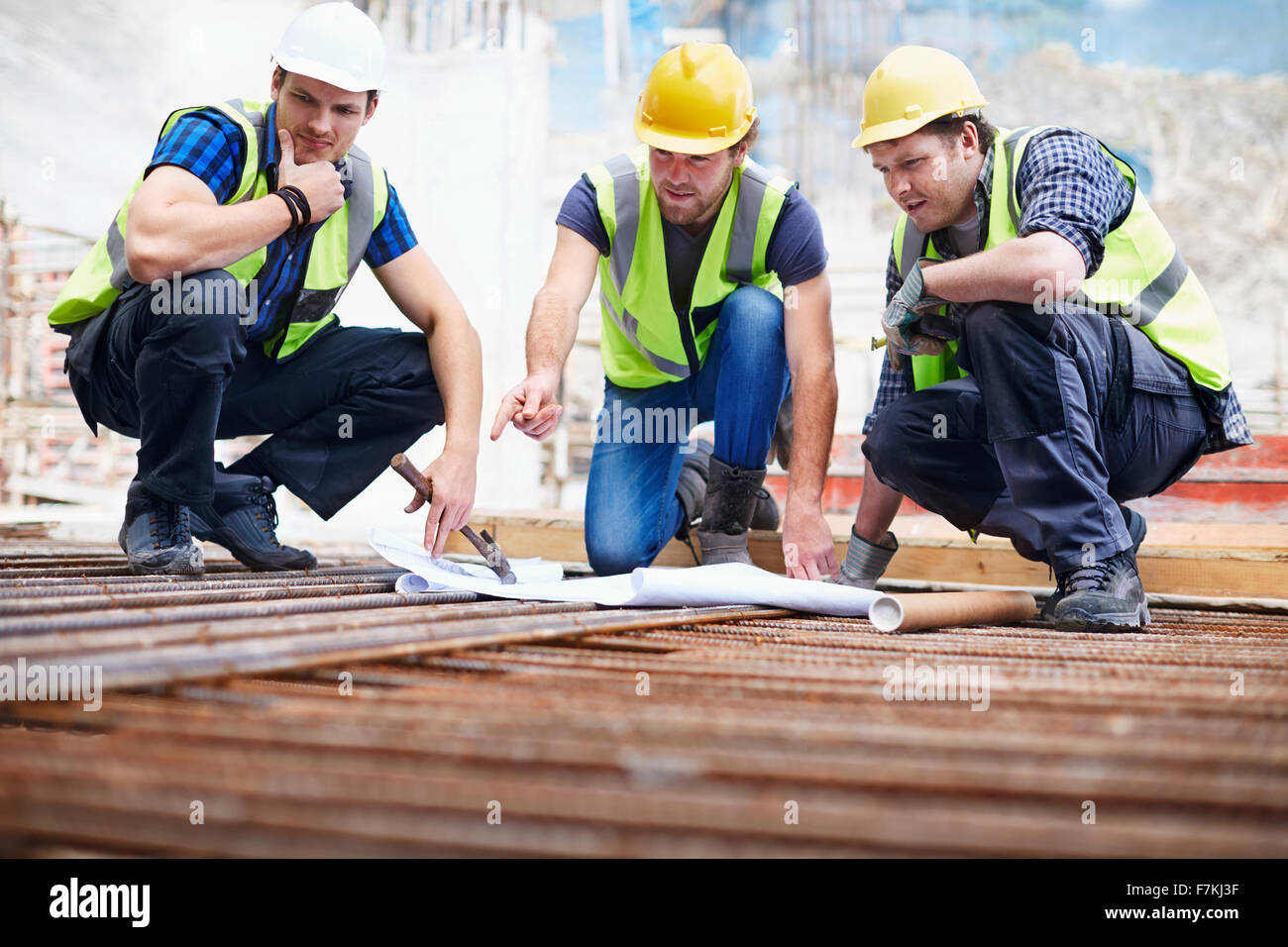 Lavoratori edili e ingegnere rivedendo blueprint al sito in costruzione Foto Stock