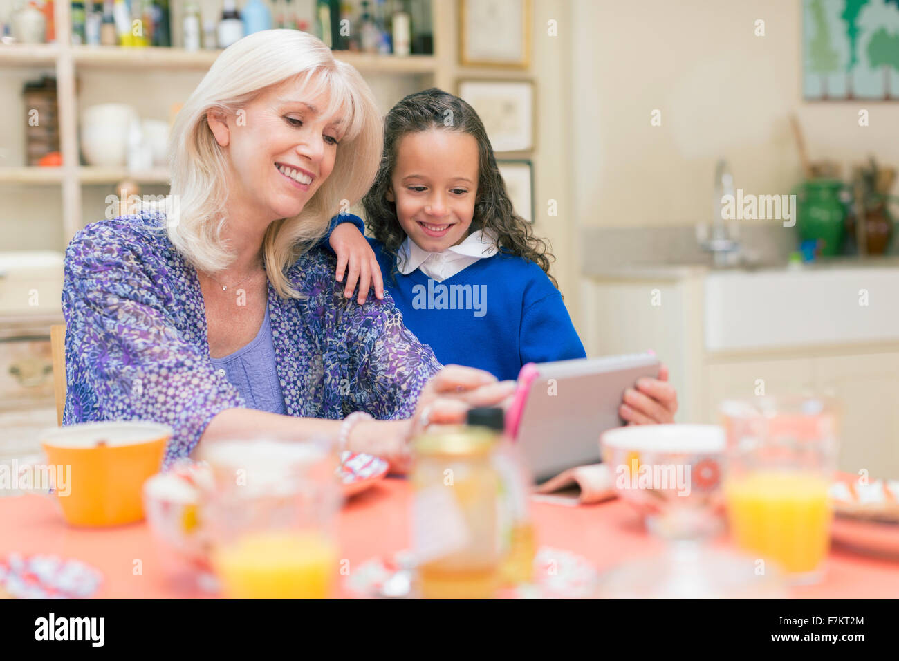 Nonna e nipote utilizzando digitale compressa al tavolo per la colazione Foto Stock