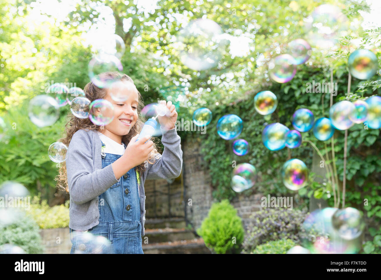 Ragazza a soffiare bolle nel cortile posteriore Foto Stock