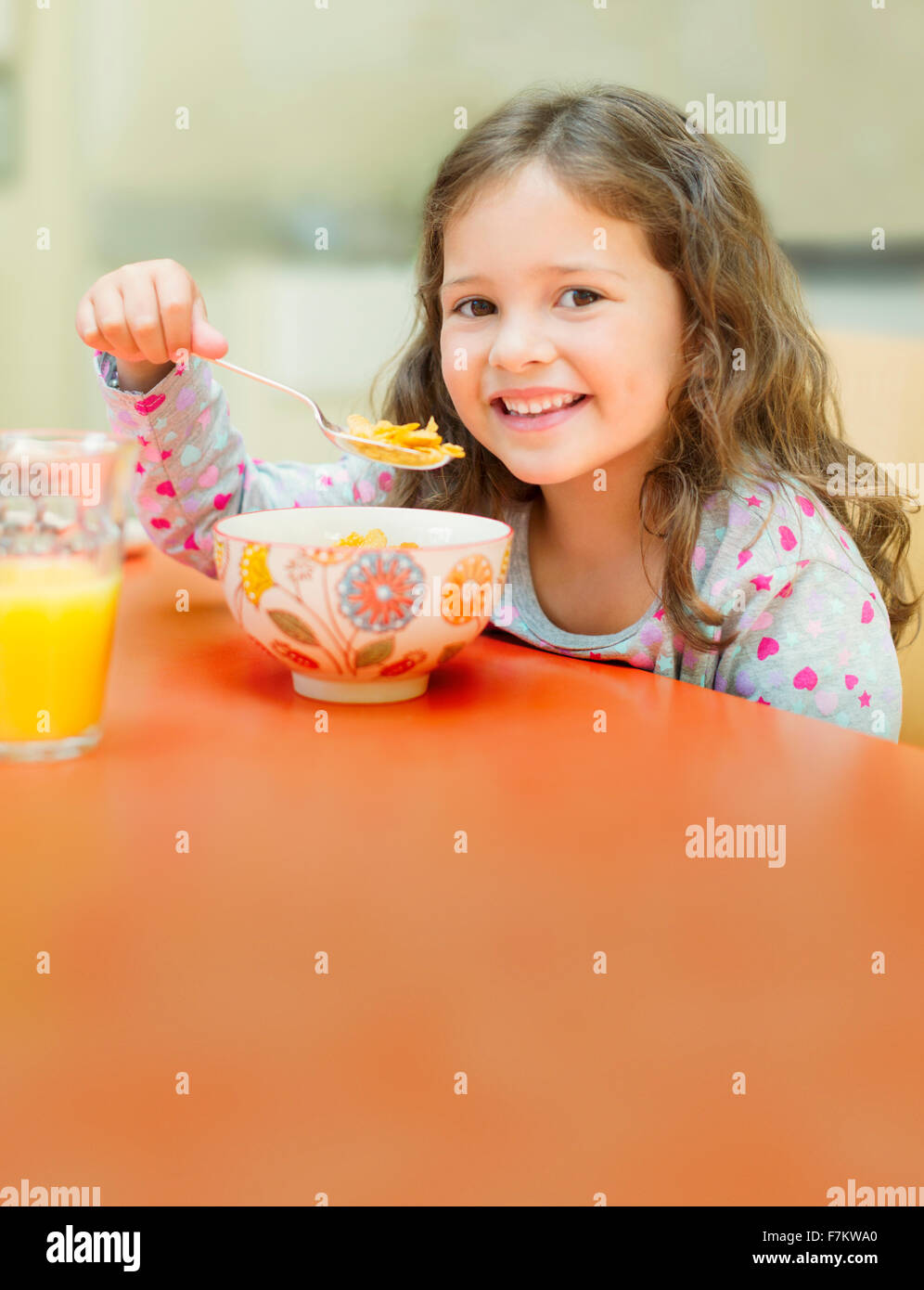 Ritratto sorridente ragazza mangiare cereali al tavolo per la colazione Foto Stock