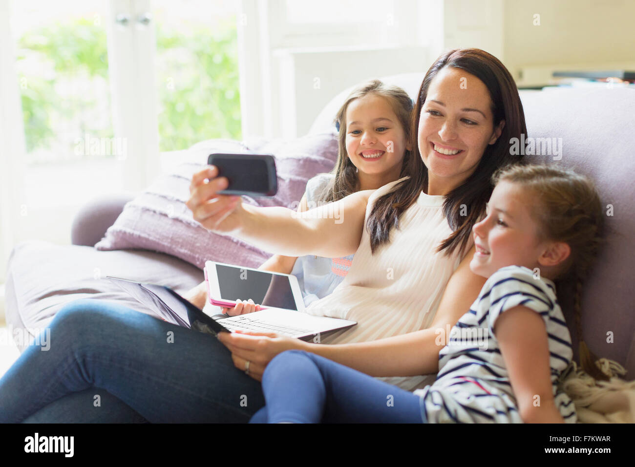 La madre e le figlie tenendo selfie sul divano Foto Stock