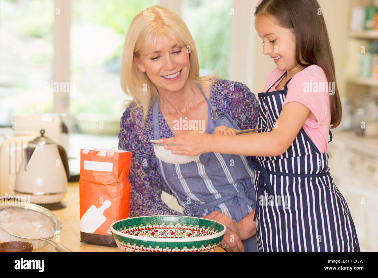 Nonna e nipote la cottura setacciare la farina in cucina Foto Stock