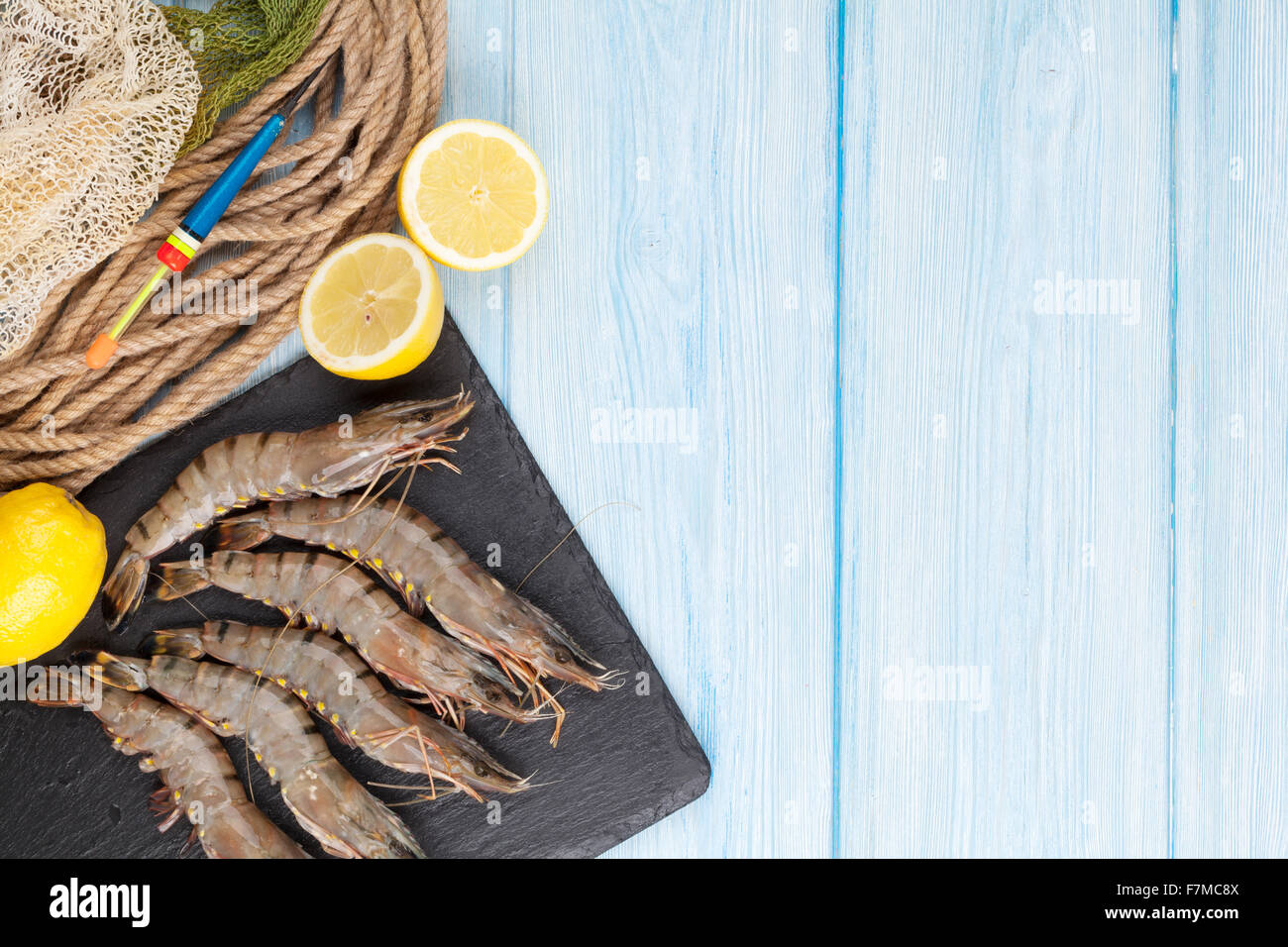 Crudo fresco gamberoni e attrezzature per la pesca su un tavolo di legno. Vista da sopra con lo spazio di copia Foto Stock