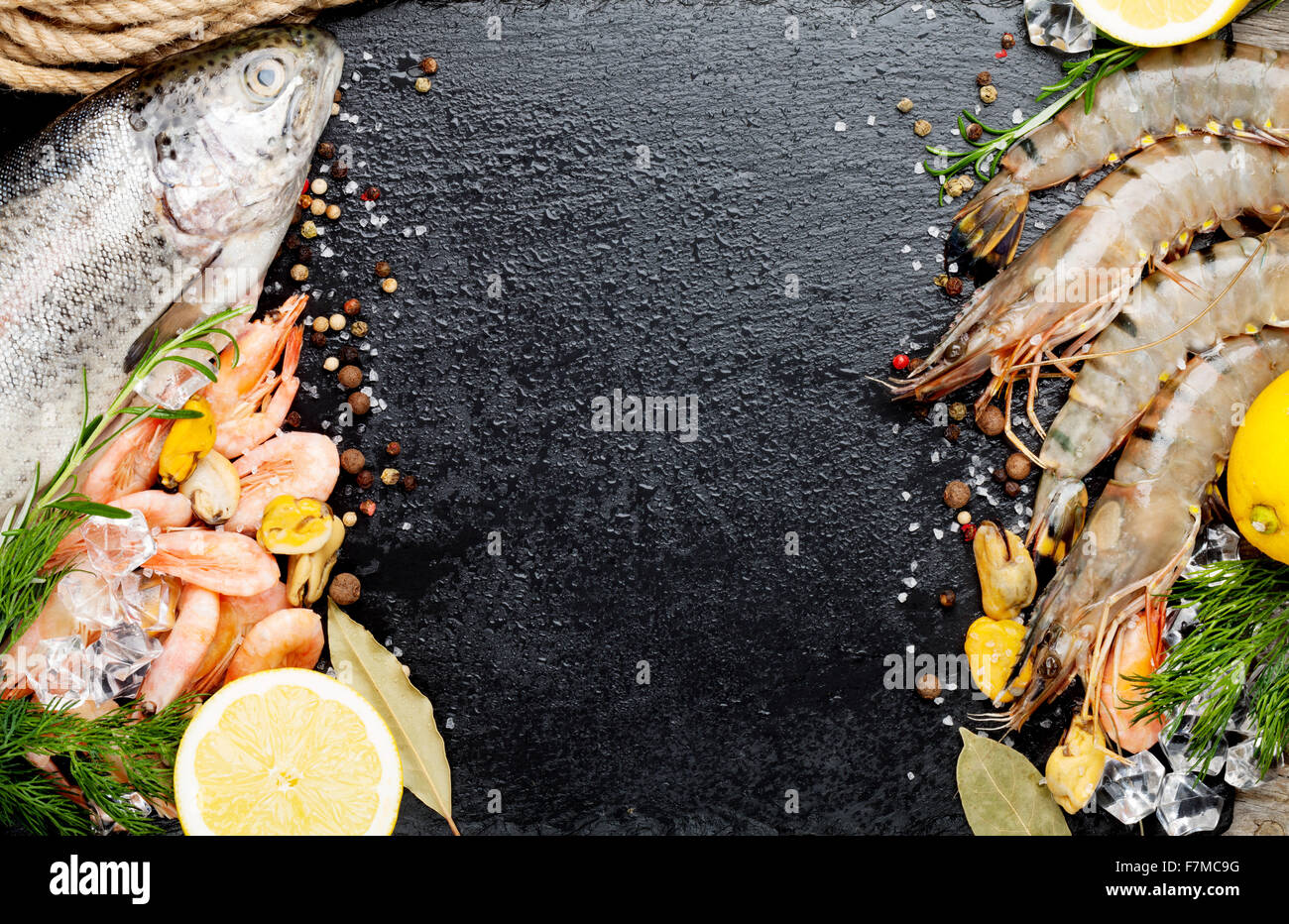 Crudo fresco il cibo del mare con spezie sulla pietra nera dello sfondo. Vista da sopra con lo spazio di copia Foto Stock