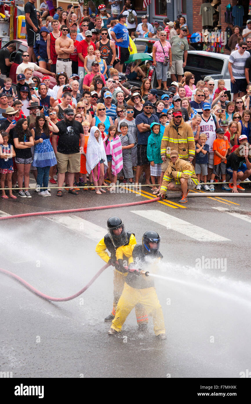 Uomini vestiti in giallo per i vigili del fuoco slickers e firehoses hanno Waterfight annuale il 4 luglio Main Street, Ouray, CO, sponsorizzato da Ouray Reparto antincendio Foto Stock
