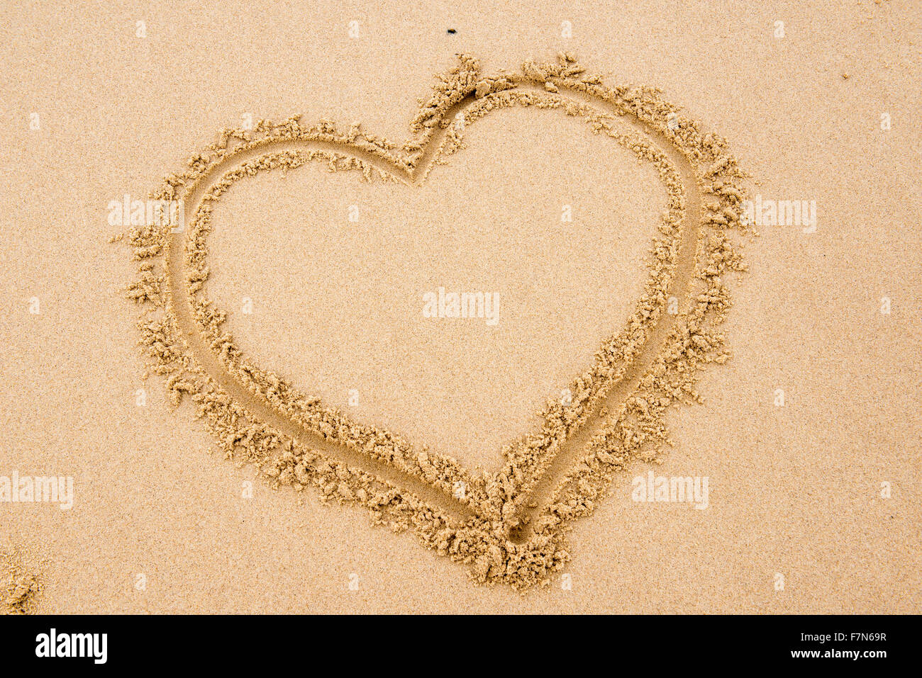 Forma di cuore disegnato nella sabbia sulla spiaggia Foto Stock