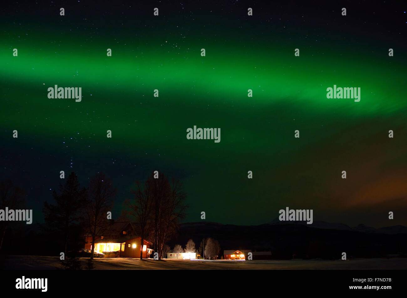Il verde forte aurora boreale su campo e di abitazioni del circolo polare artico paesaggio invernale Foto Stock