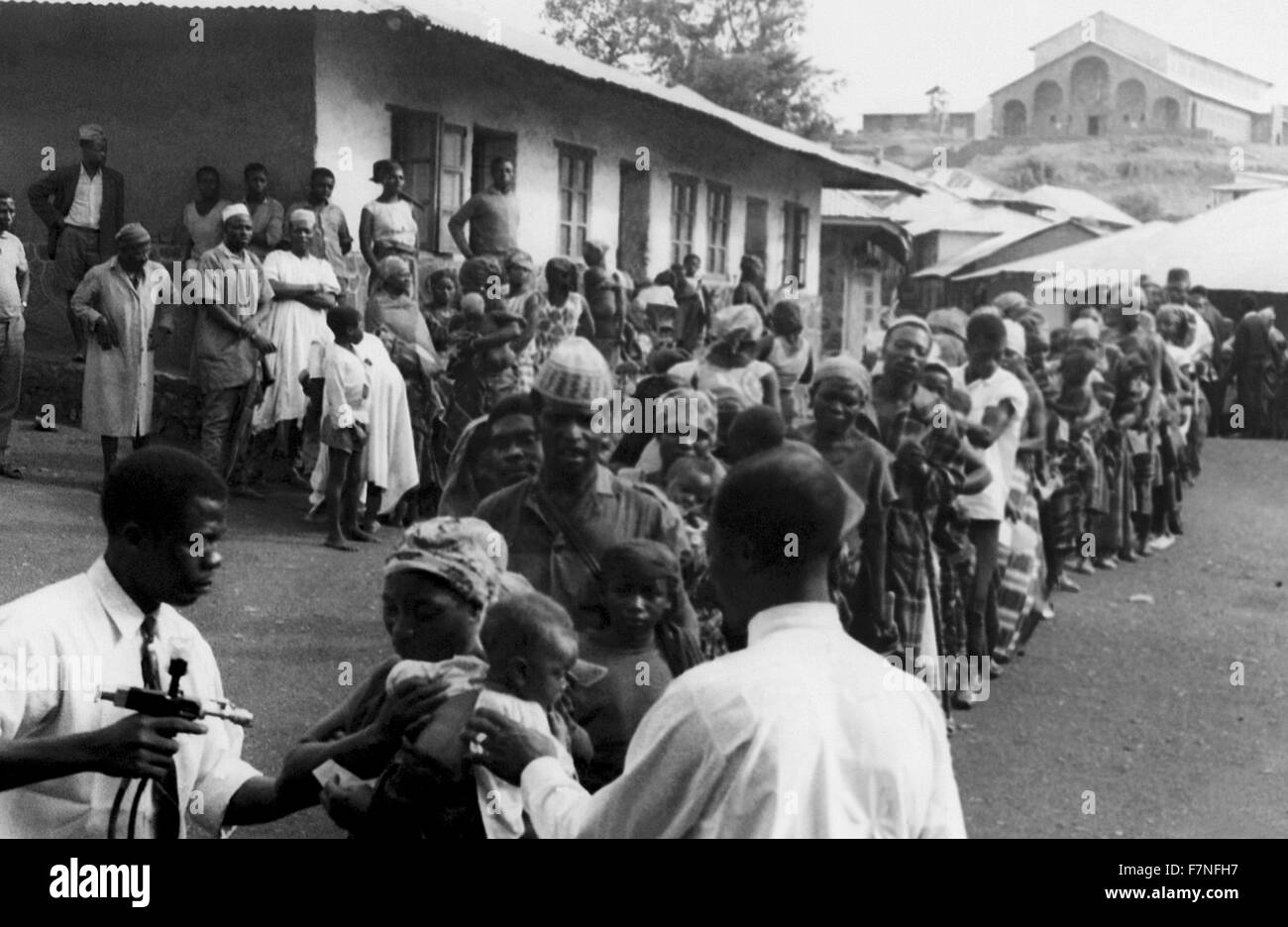 Catturati nella zona tribale del Camerun occidentale conosciuta come Banso, questa fotografia storica rappresentata la linea dei paesani che attende il vaiolo e la vaccinazione contro il morbillo durante il paese della partecipazione in tutto il mondo gli sforzi per erradicate, e il controllo di tali malattie nel corso degli anni sessanta. Foto Stock