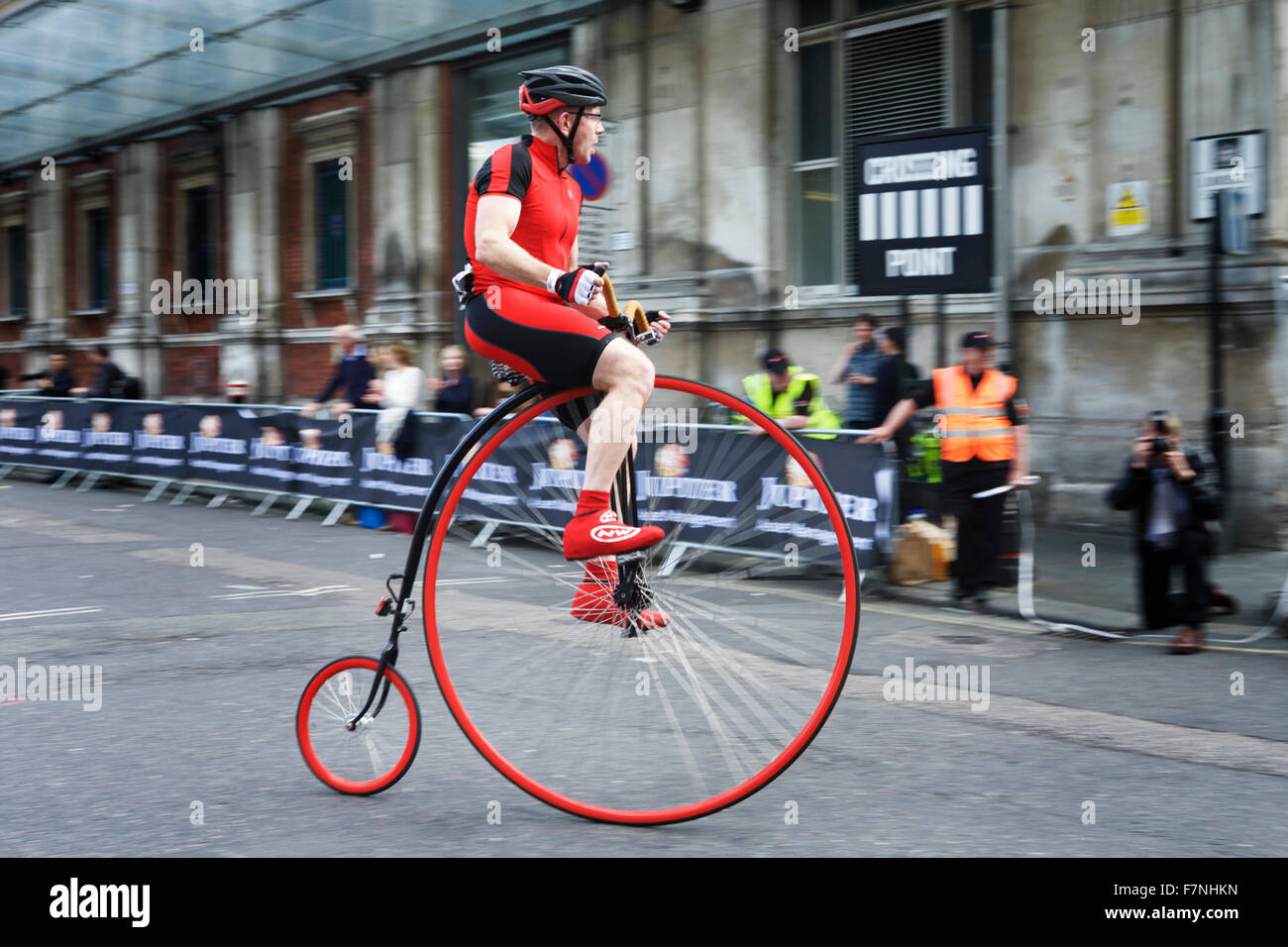 Penny Farthing bicicletta e pilota al Giove Nocturne gare ciclo: racing in giro per le strade di Smithfield Market, London, Regno Unito Foto Stock