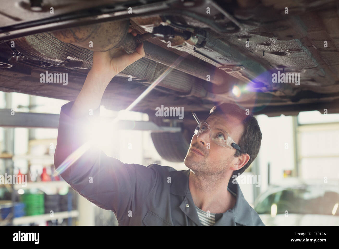 Lavoro meccanico sotto auto nel negozio di riparazioni auto Foto Stock