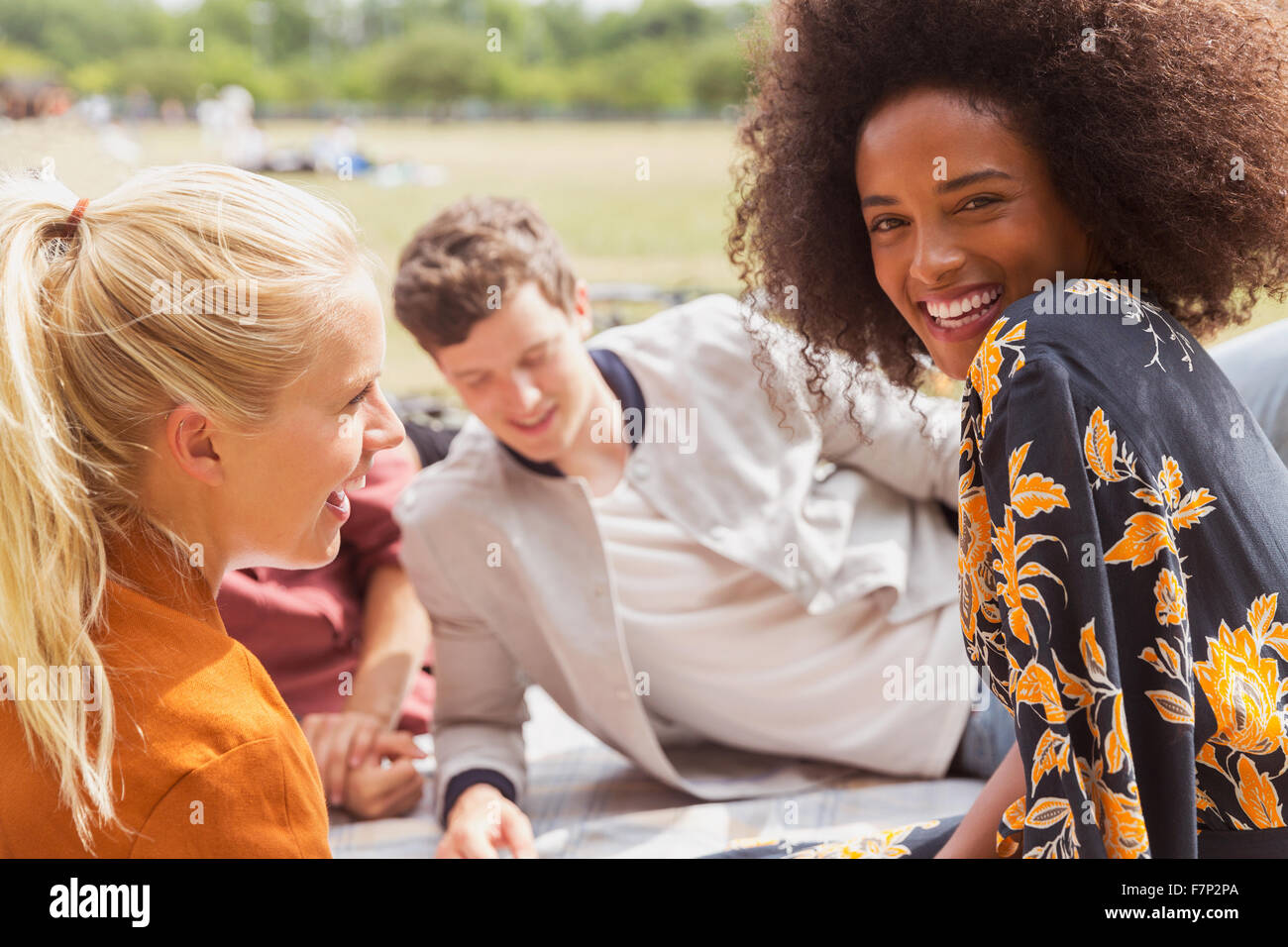 Ritratto di donna sorridente appendere fuori con gli amici nel soleggiato parco Foto Stock