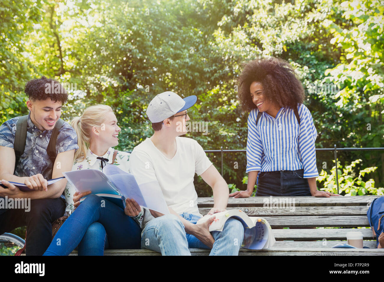 Studenti del college appendere fuori a studiare su una panchina nel parco Foto Stock