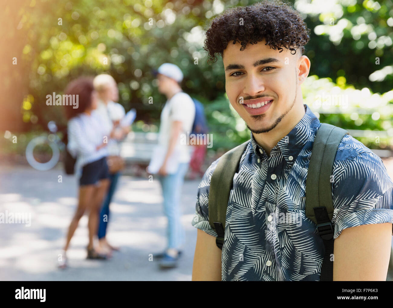 Ritratto uomo sorridente con ricci capelli neri in posizione di parcheggio Foto Stock