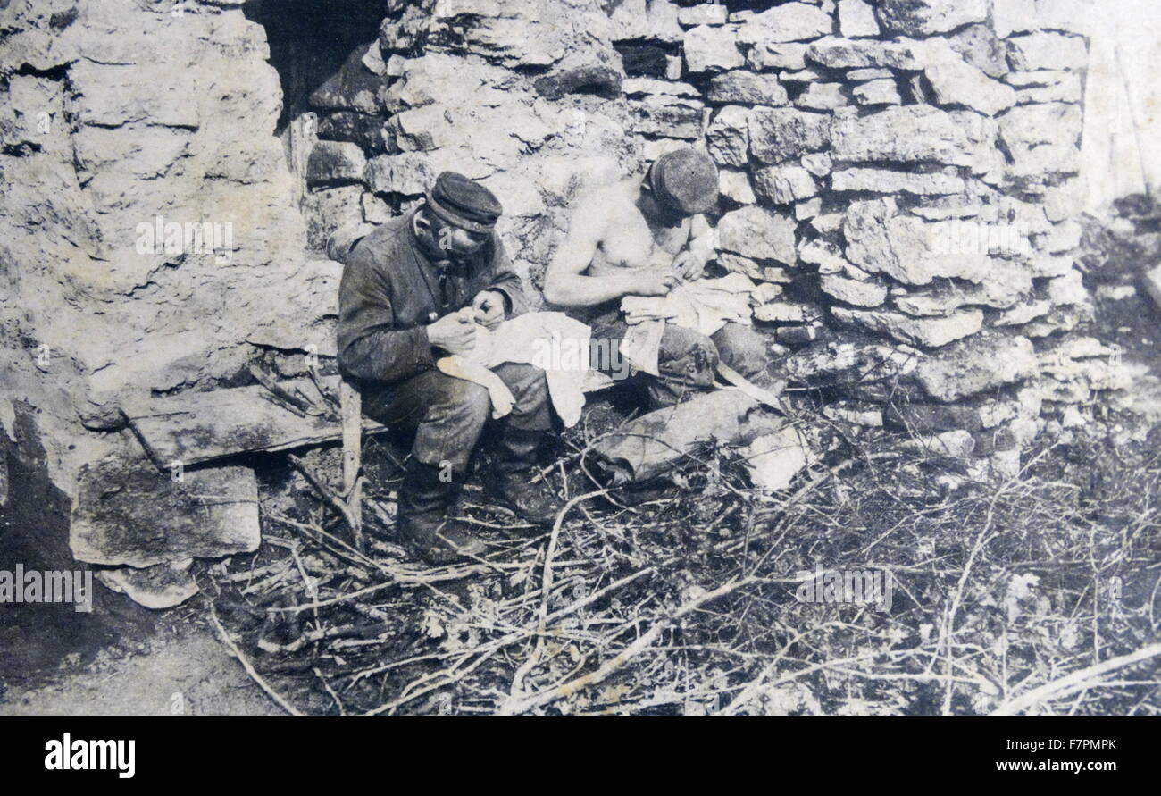 Fotografia di soldati tedeschi a caccia di pidocchi sul loro abbigliamento nelle trincee. Datata 1914 Foto Stock