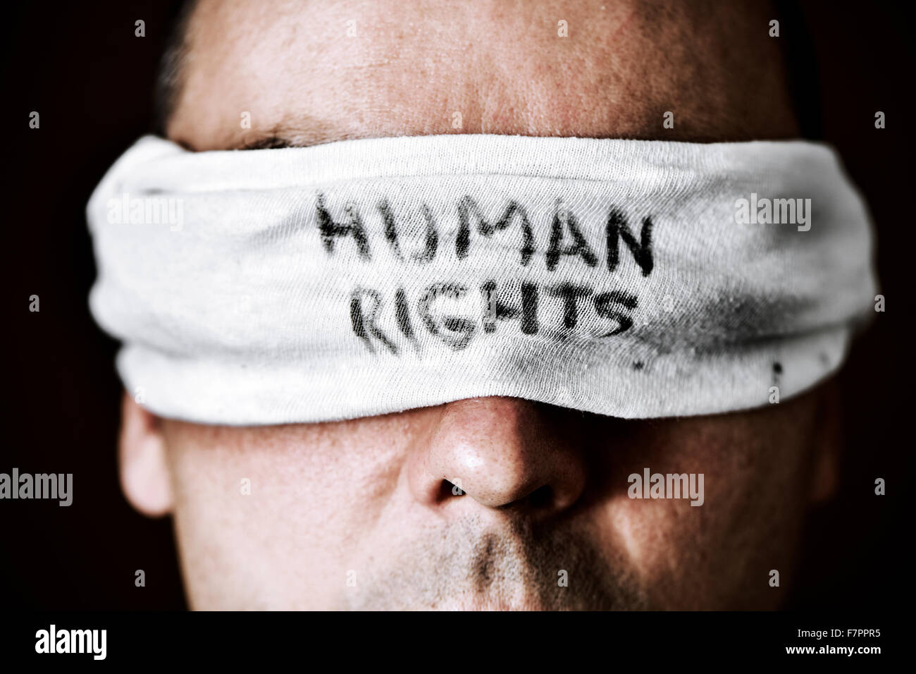 Primo piano di un giovane uomo con una benda agli occhi con il testo dei diritti umani scritta in essa come un simbolo di oppressione o offrono Foto Stock