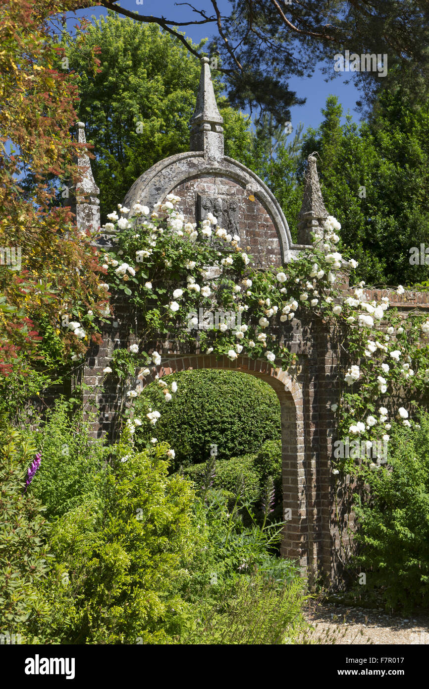 Rose-coperta arco in mattoni nel muro giardino, Nymans, West Sussex, nel mese di luglio. Foto Stock