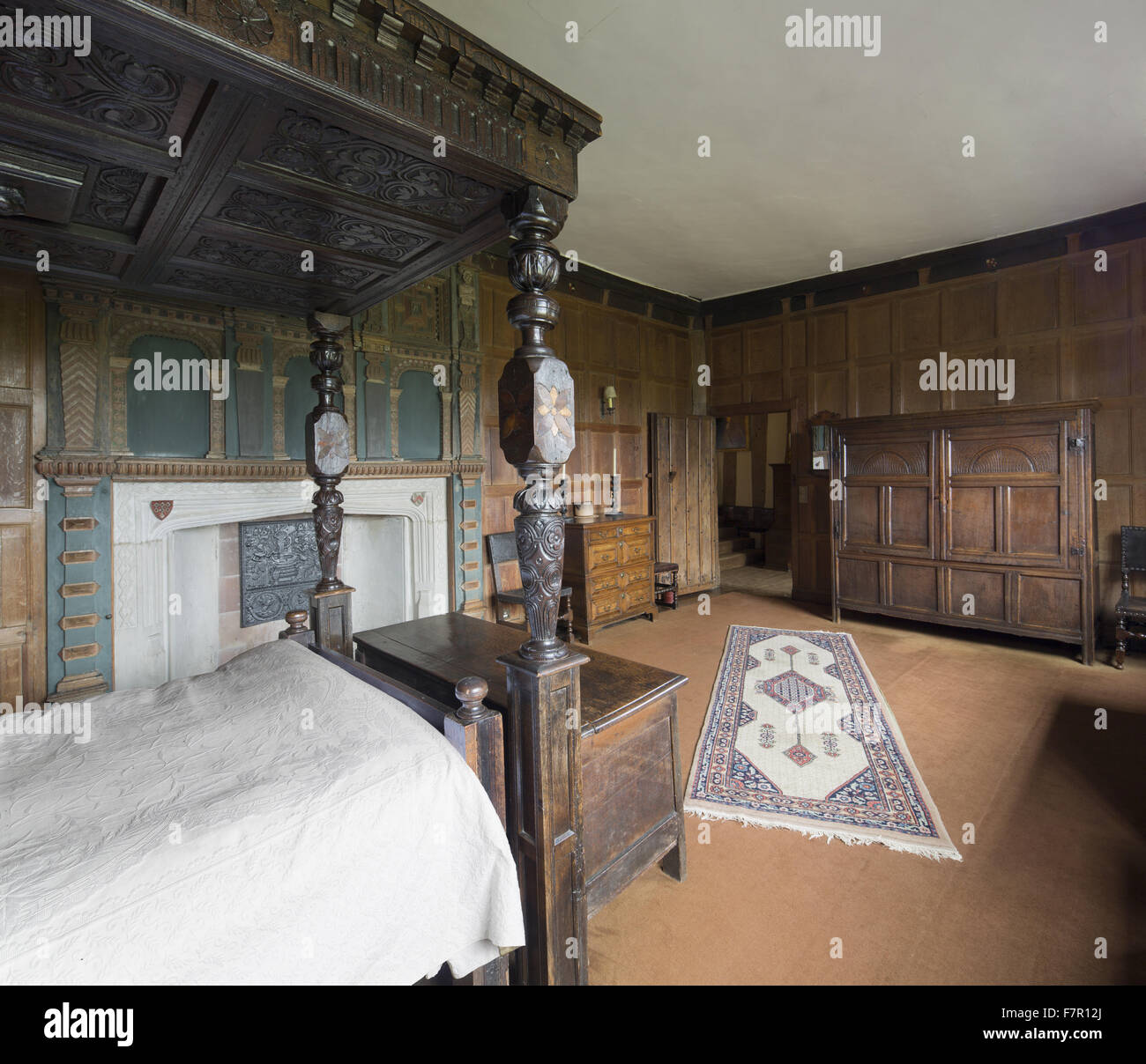 Henry Ferrers la camera da letto, Baddesley Clinton, Warwickshire. Il intagliato e intarsiato a quattro posti letto in legno di quercia è stata fatta dal XVII secolo frammenti, che sono stati messi insieme nel diciannovesimo secolo. La caminiera include i bracci del Ferrers di G Foto Stock