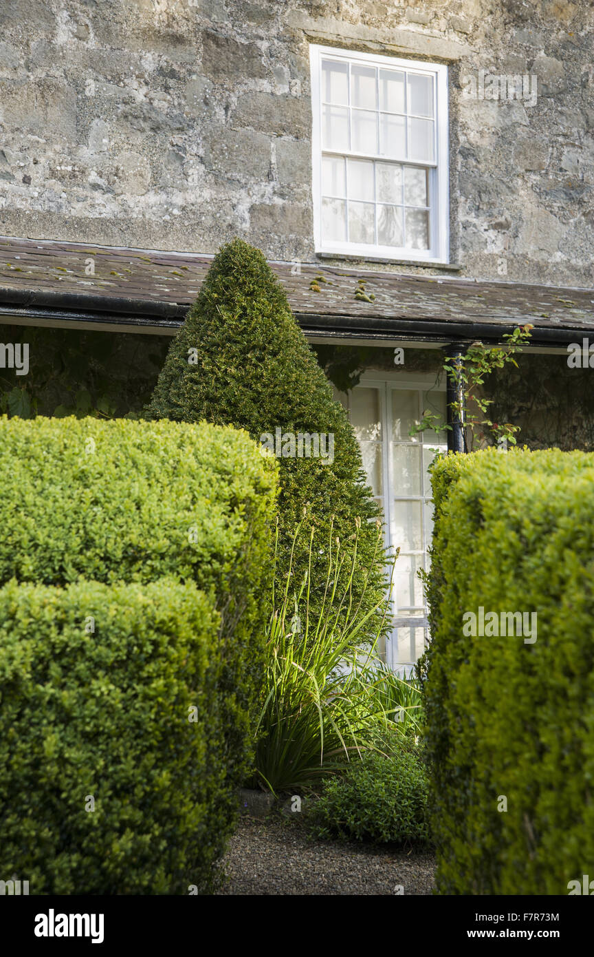 Il lato sud della casa, mostrando una veranda, siepi di bosso e agganciata yew topiaria da a Plas yn Rhiw, Gwynedd. I giardini di Plas yn Rhiw hanno viste spettacolari su Cardigan Bay. Foto Stock