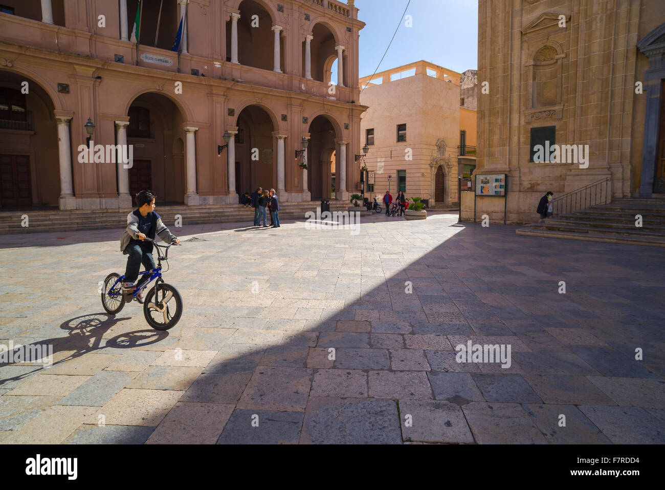 Ragazzo in bicicletta Italia, un ragazzo gira in bicicletta intorno alla piazza della Repubblica a Marsala, Sicilia, Italia Foto Stock