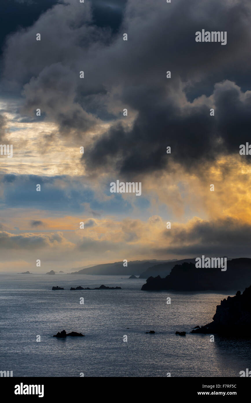 Scogliere sul mare A la Pointe de Penharn all alba con nuvole temporalesche, Cléden-Cap-Sizun, Finistère Bretagna, Francia Foto Stock