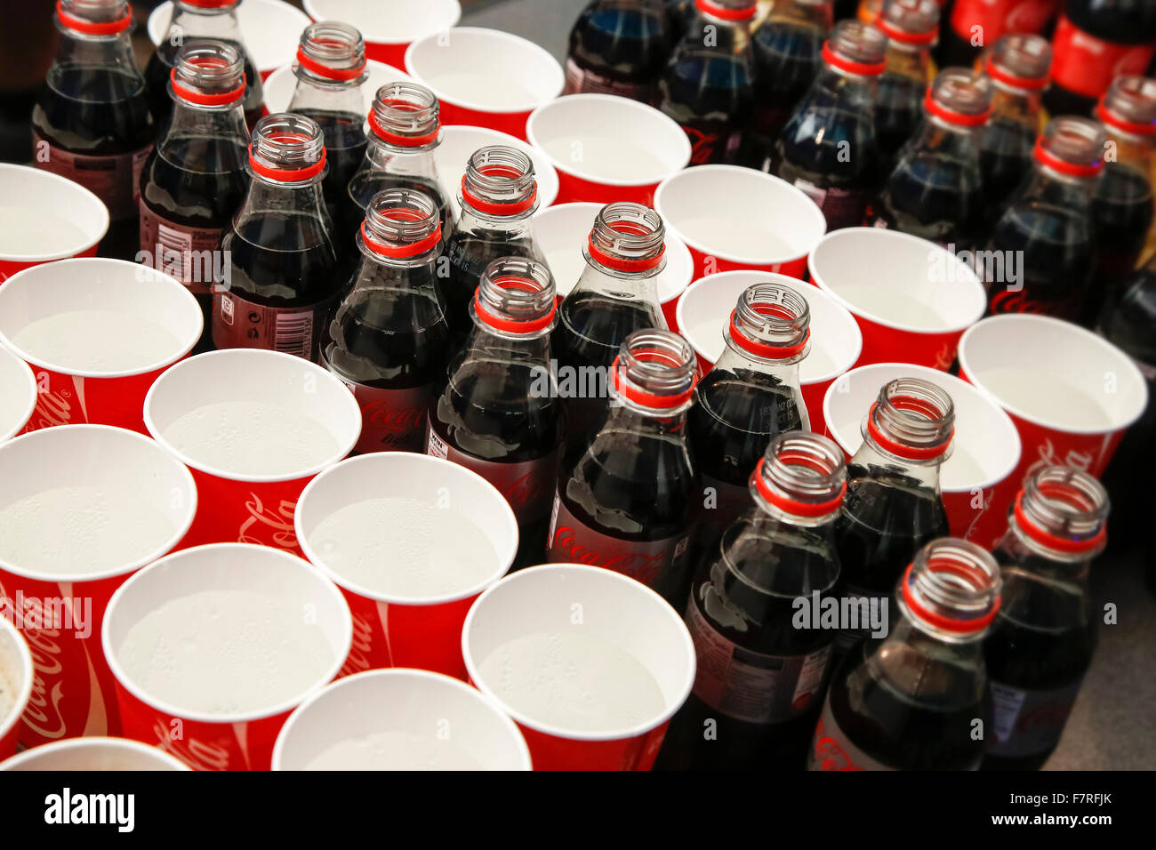 Plastica aperta la Coca Cola bottiglie e bicchieri usa e getta con acqua frizzante a caso Foto Stock