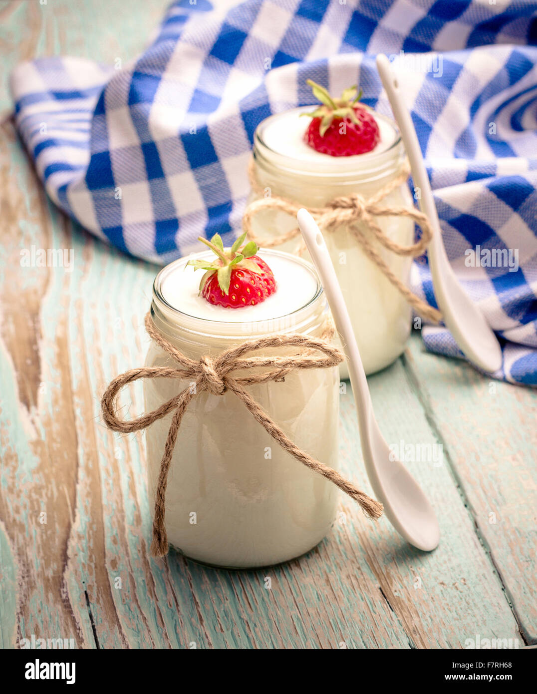 Due yogurt greco, di vetro con le fragole e il cucchiaio in ceramica, verticale Foto Stock